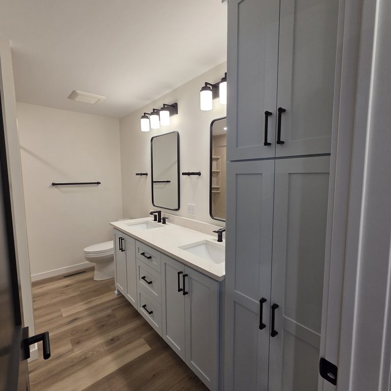 Gray shaker double vanity with a full-height linen tower and black hardware by MDR Design-Build-Remodel