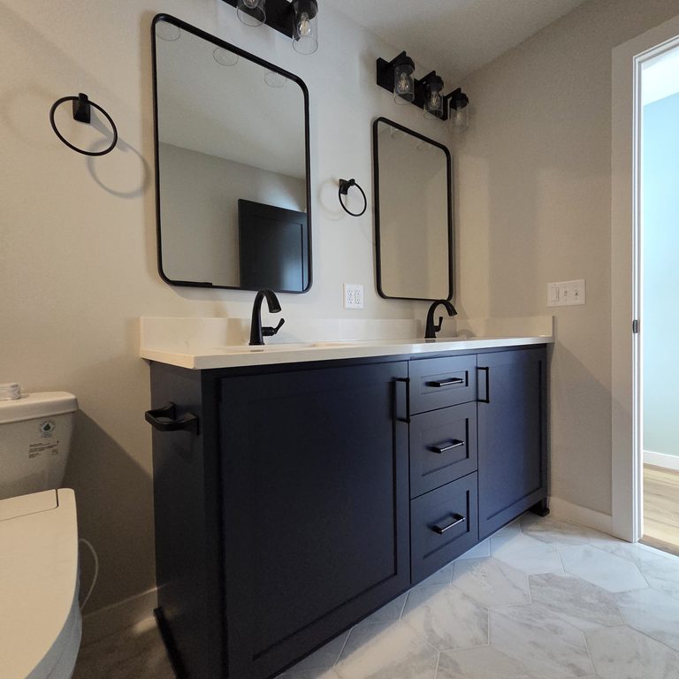 Dark navy bathroom vanity with black-framed mirrors and light fixtures by MDR Design-Build-Remodel