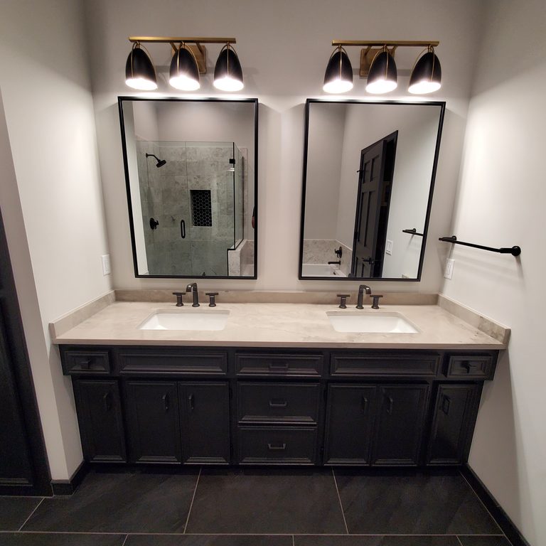 Black double vanity with a light stone-look top, black-framed mirrors and bell sconces by MDR Design-Build-Remodel